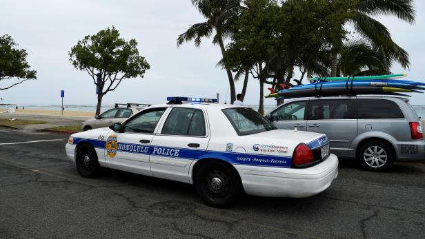 A Honolulu police car drives thru Ala Moana beach park warning beach goers as Hurricane Lane approaches Honolulu.