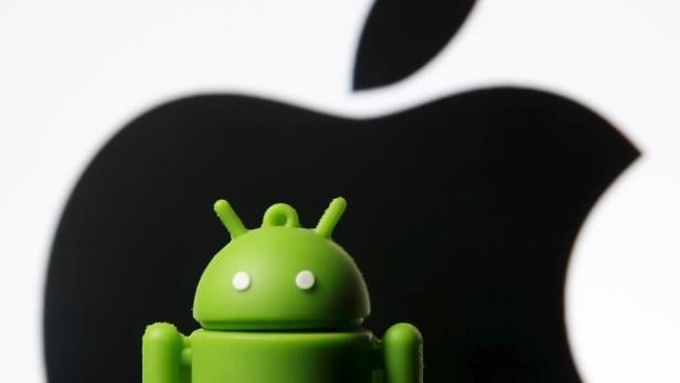 Android mascot is seen in front of a displayed logo of Apple in this photo illustration taken in Zenica