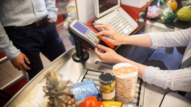 Cashier Using Payment Terminal in Supermarket