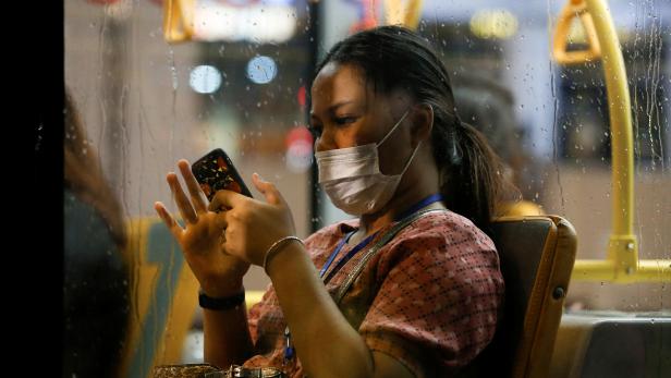 A woman wearing a protective mask uses a smartphone as she travels on a bus during rush hour, after Indonesia confirmed its first cases of COVID-19, in Jakarta