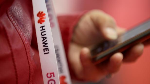 FILE PHOTO: An attendee wears a badge strip with the logo of Huawei and a sign for 5G at the World 5G Exhibition in Beijing