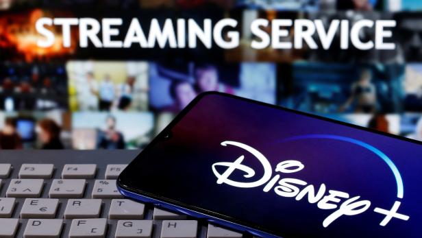 FILE PHOTO: Smartphone with displayed "Disney" logo is seen on the keyboard in front of displayed "Streaming service" words in this illustration