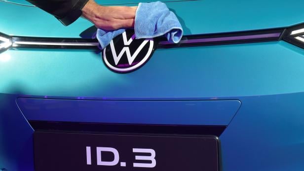 An employee cleans a logo of a new car after a ceremony marking start of the production of a new electric Volkswagen model ID.3 in Zwickau