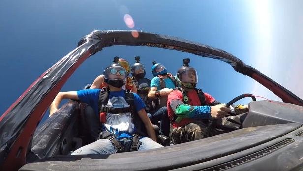 Ein Skydiving-Team lässt sich in einem Auto sitzend vom Himmel fallen