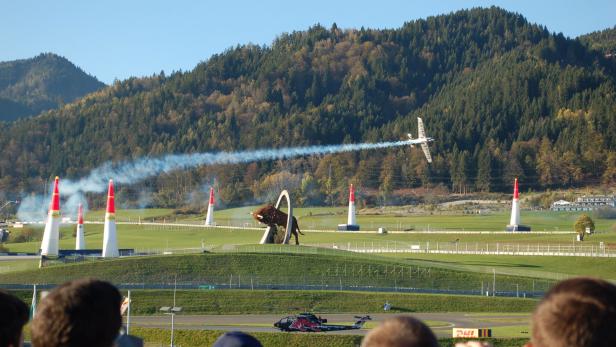 Für alle, denen der Begriff Red Bull Air Race nichts sagt: Es handelt sich um einen internationalen Wettbewerb, bei dem Piloten mit Propellerflugzeugen im Slalom durch Tore aus aufblasbaren Pylonen fliegen.