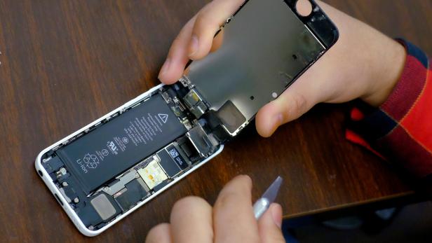 FILE PHOTO: A man tries to repair an iPhone in a repair store in New York