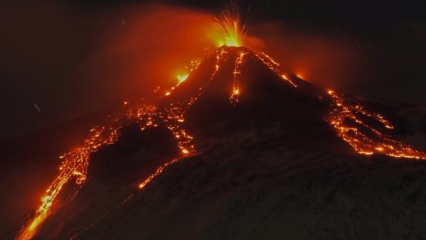 An eruption from Mount Etna lights up the sky during the night, seen from Fornazzo