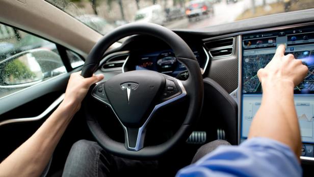 Ein Fahrer bedient den Touchscreen eines Tesla-Autos.