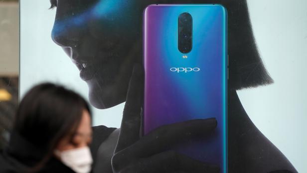 A woman walks past an Oppo advertisement at a shopping mall in Shanghai