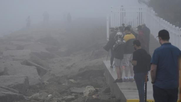 Spectators stand in the fog to try and view the test launch of SpaceX rocket flight SN11