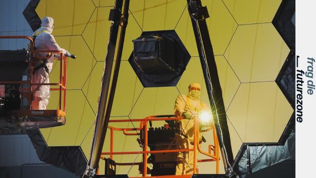 Ein Arbeiter vor dem riesigen Spiegel des James Webb Weltraumteleskops