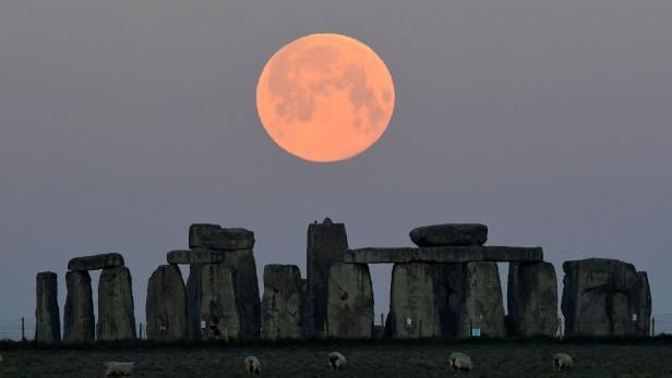 The full moon, known as the "Super Pink Moon", sets behind Stonehenge stone circle near Amesbury