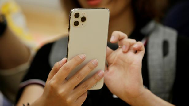 FILE PHOTO: A woman holds an iPhone 11 Pro Max in September 2019 at the Apple Store in Beijing