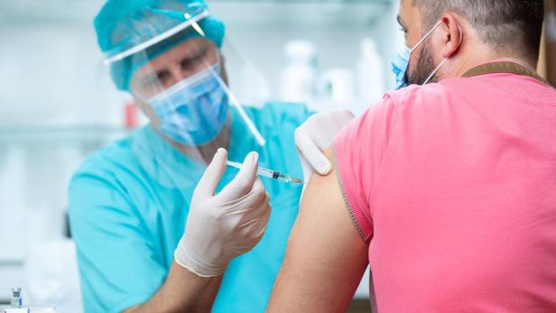 Doctor wearing protective workwear injecting vaccine into patient's arm