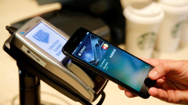 FILE PHOTO: Man uses iPhone 7 smartphone to demonstrate mobile payment service Apple Pay at cafe in Moscow