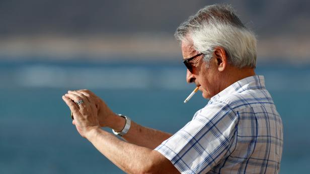 A man smokes a cigarette while taking a picture with his cell phone during the spread of the coronavirus disease (COVID-19) pandemic, in Las Palmas