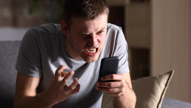 Angry man with a mobile phone at home