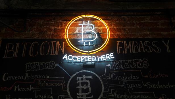 A neon logo of virtual cryptocurrency Bitcoin is seen at the Bitcoin Embassy bar in this illustration