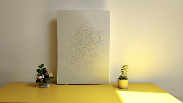 Der Symfonisk Bilderrahmen ist eines der Sonos-Produkte, die in Zusammenarbeit mit Ikea entstanden. Ikea Symfonisk Bilderrahmen-Lautsprecher auf einem gelben Tisch an die Wand gelehnt