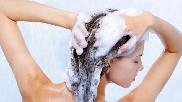 Frau wäscht sich ihre Haare mit Shampoo in der Dusche