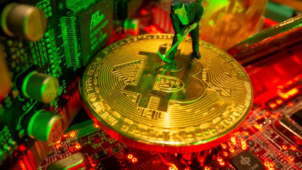 FILE PHOTO: A small toy figure and representations of the virtual currency Bitcoin stand on a motherboard in this picture illustration