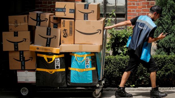 FILE PHOTO: FILE PHOTO: An Amazon delivery worker pulls a delivery cart full of packages during its annual Prime Day promotion in New York
