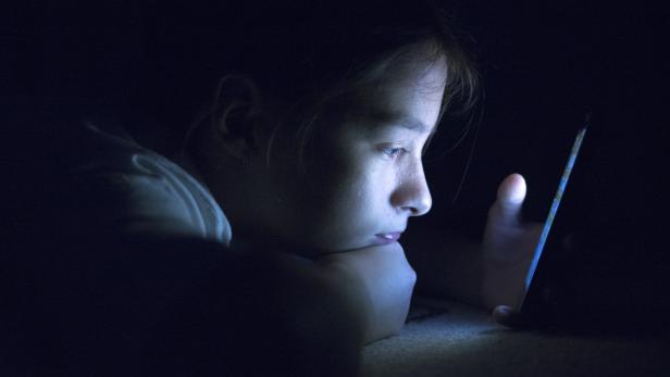 Teenager sending email from smart phone in her bed