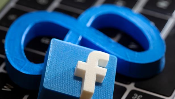 A 3D printed Facebook's new rebrand logo Meta and Facebook logo are placed on laptop keyboard in this illustration