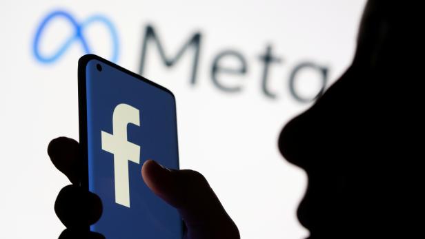 FILE PHOTO: Woman holds smartphone with Facebook logo in front of a Meta logo in this illustration picture