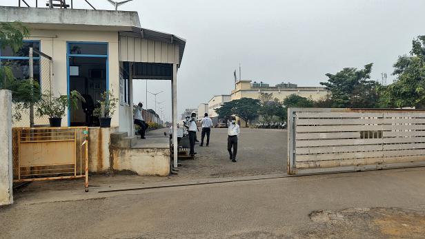 Private security guards stand at the entrance of a closed plant of Foxconn India unit, near Chennai