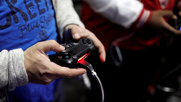 FILE PHOTO: Visitors play games on PlayStation 4 (PS4) at the Paris Games Week, a trade fair for video games in Paris