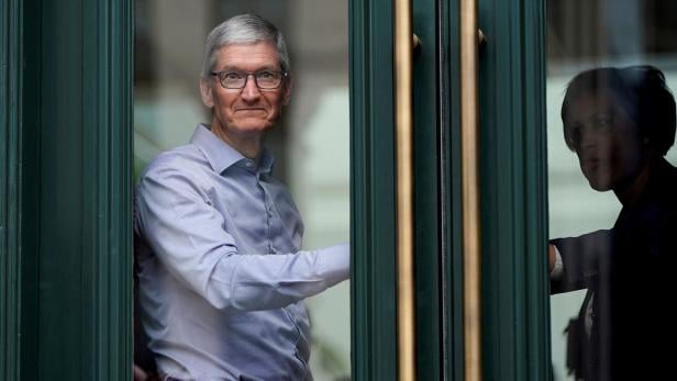 FILE PHOTO: pple Chief Executive Officer Tim Cook watches customers awaiting the grand opening of the new Apple Carnegie Library store in Washington