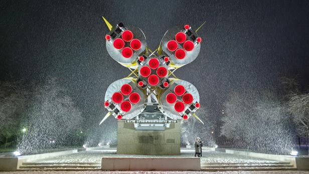 People take a selfie in front of the Soyuz rocket that is set as a monument during snowfall in the town of Baikonur