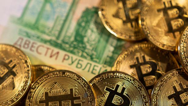 Illustration shows Russian rouble banknotes and representations of the cryptocurrency Bitcoin