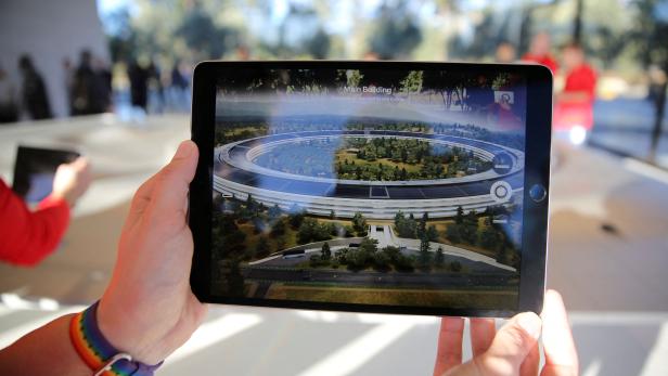 FILE PHOTO: An Apple employee uses an iPad with an augmented reality app on it to show off features of the new Apple Park at the Apple Visitor Center in Cupertino