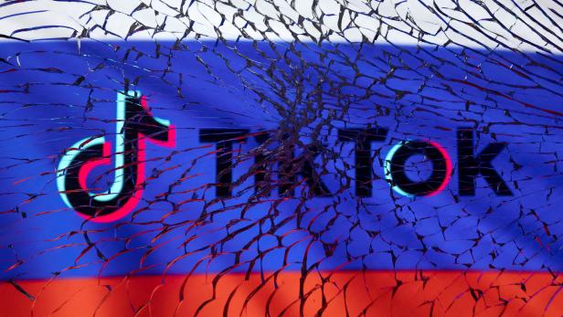Illustration shows TikTok logo and Russian flag through broken glass