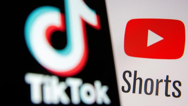Tik Tok logo is seen on a smartphone in front of displayed Youtube Shorts logo in this illustration taken