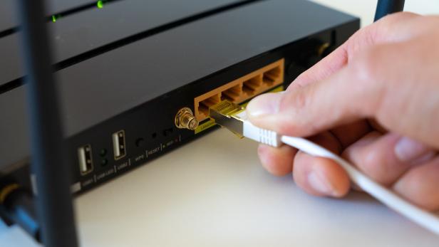 Person steckt Kabel in einen Router