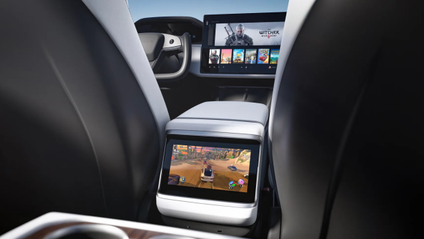 Blick zwischen den Rücksitzen eines Teslas auf zwei Displays mit Spielen drauf