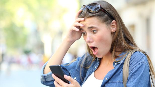 Shocked teen checking phone content in the street