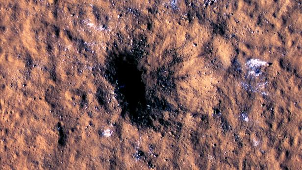 Durch Meteoritentreffer verursachter Krater am Mars, neben dem Eisbrocken zu sehen sind
