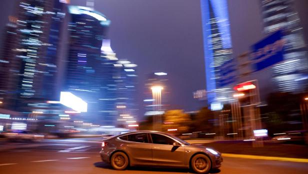FILE PHOTO: A Tesla electric car drives past a crossing in Shanghai