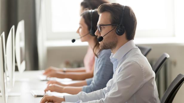 Male call center agent in wireless headset consulting online client