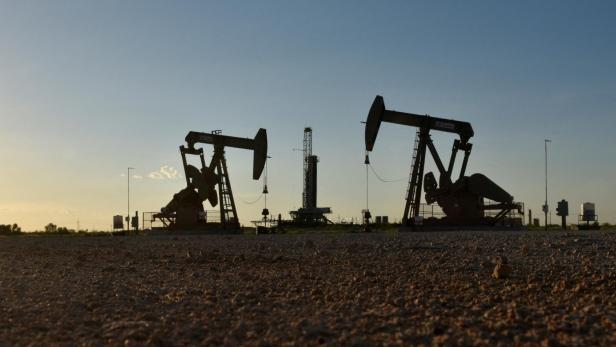 FILE PHOTO: Pump jacks operate in front of a drilling rig in an oil field in Midland