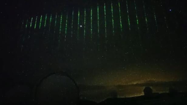 Laserstrahlen von einem Satellit am Nachthimmel über dem Subaru Teleskop auf Hawaii