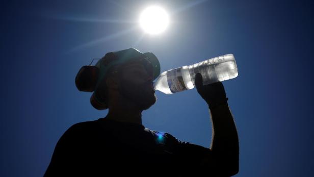 A worker drinks water on a road site in Aigrefeuille-sur-Maine