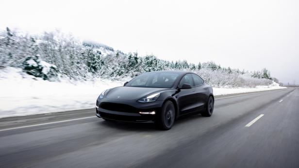 Tesla Model 3 fährt durch winterliche Landschaft