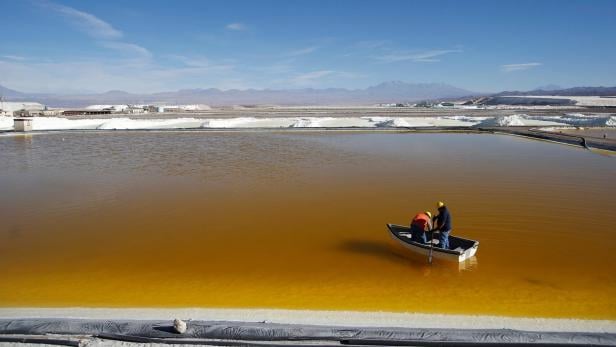 FILE PHOTO: Workers use a boat to take samples from a brine pool at the Rockwood Lithium plant on the Atacama salt flat