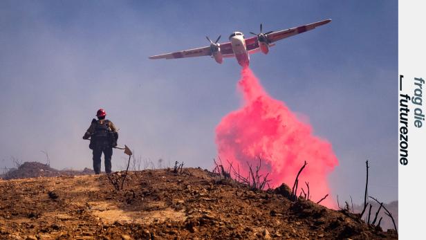 Löschflugzeug versprüht leuchtend rotes brandhemmendes Mittel über verbranntem Wald