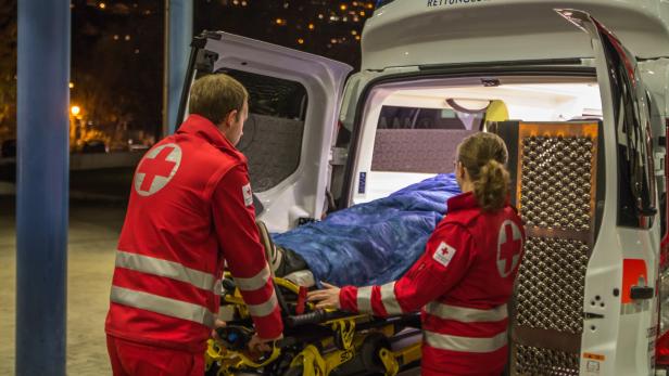 Zwei Sanitäter schieben eine Trage in einen Rettungswagen des Rettungsdienstes Tirol.